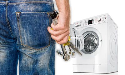 Person in Jeans mit Werkzeug in der Hand steht vor einer Waschmaschine.